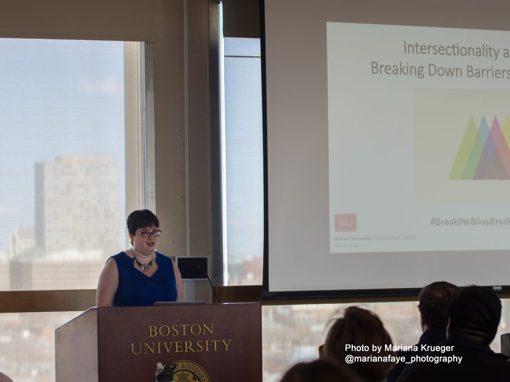 Nikki Friedman stands at Boston University podium talking to attendees listening. 