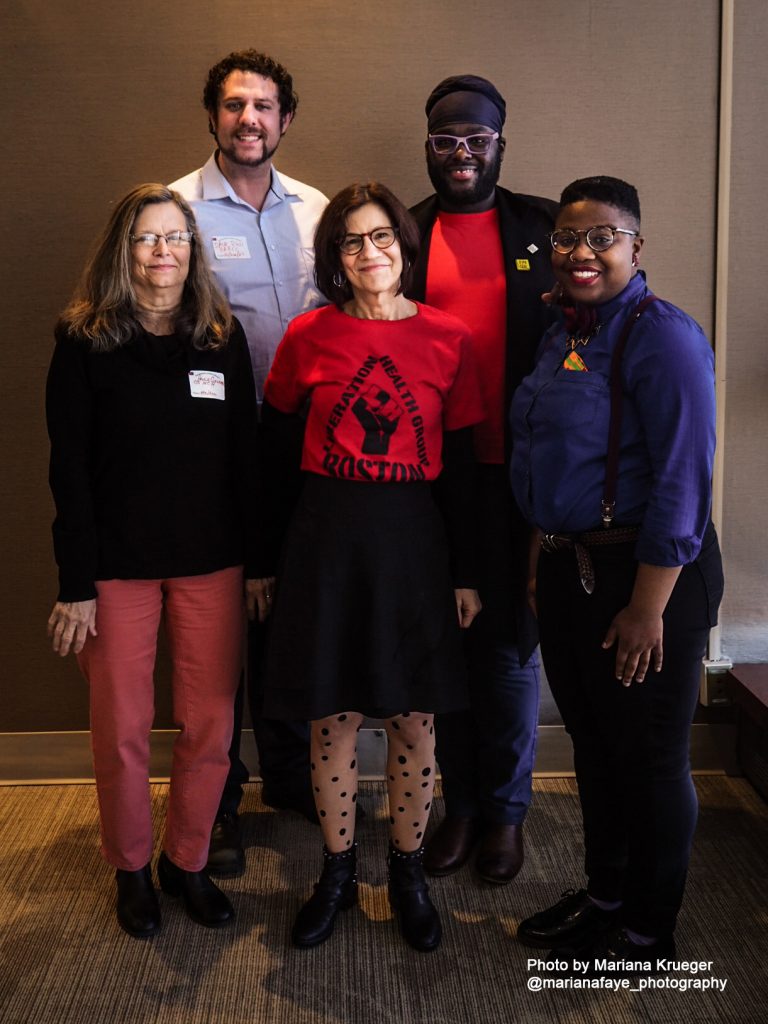 Group of five people standing smiling at the camera.